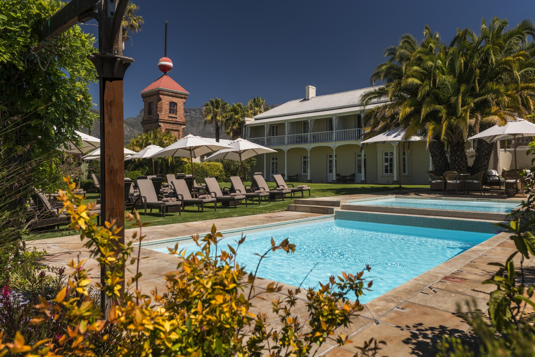 Dock-house-Pool-area A heritage-style garden with a swimming pool and loungers at one of the luxury hotels in Cape Town