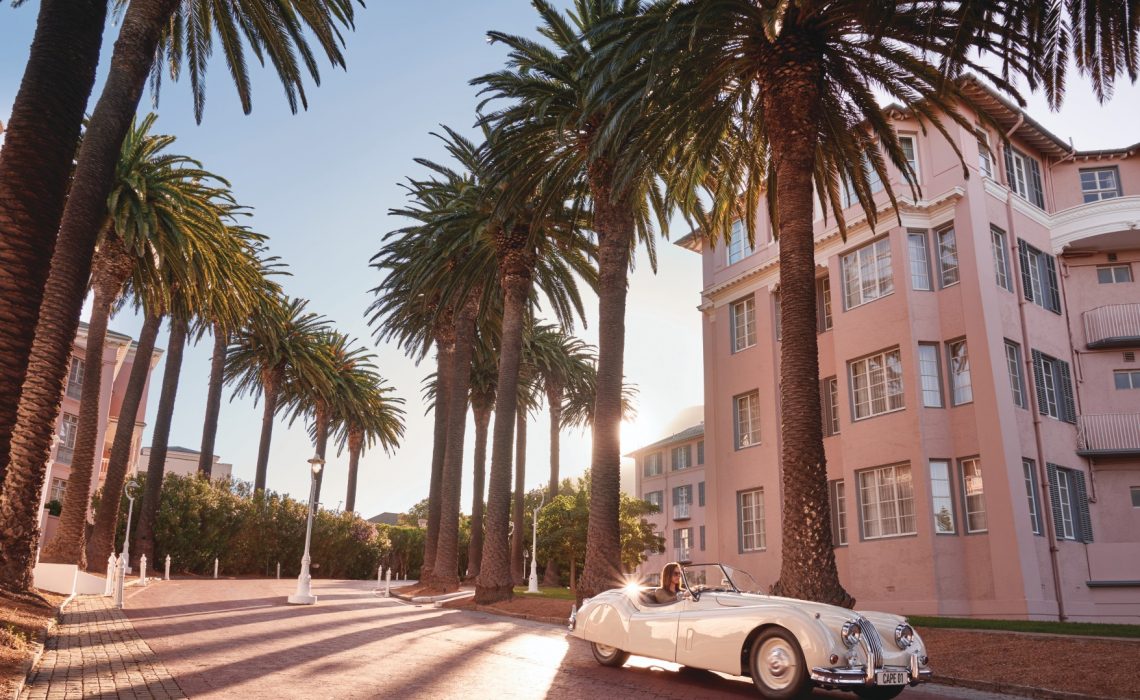 exterior-mount-nelson-hotel A vintage car parked beneath towering palms outside Mount Nelson, one of the grand luxury hotels in Cape Town