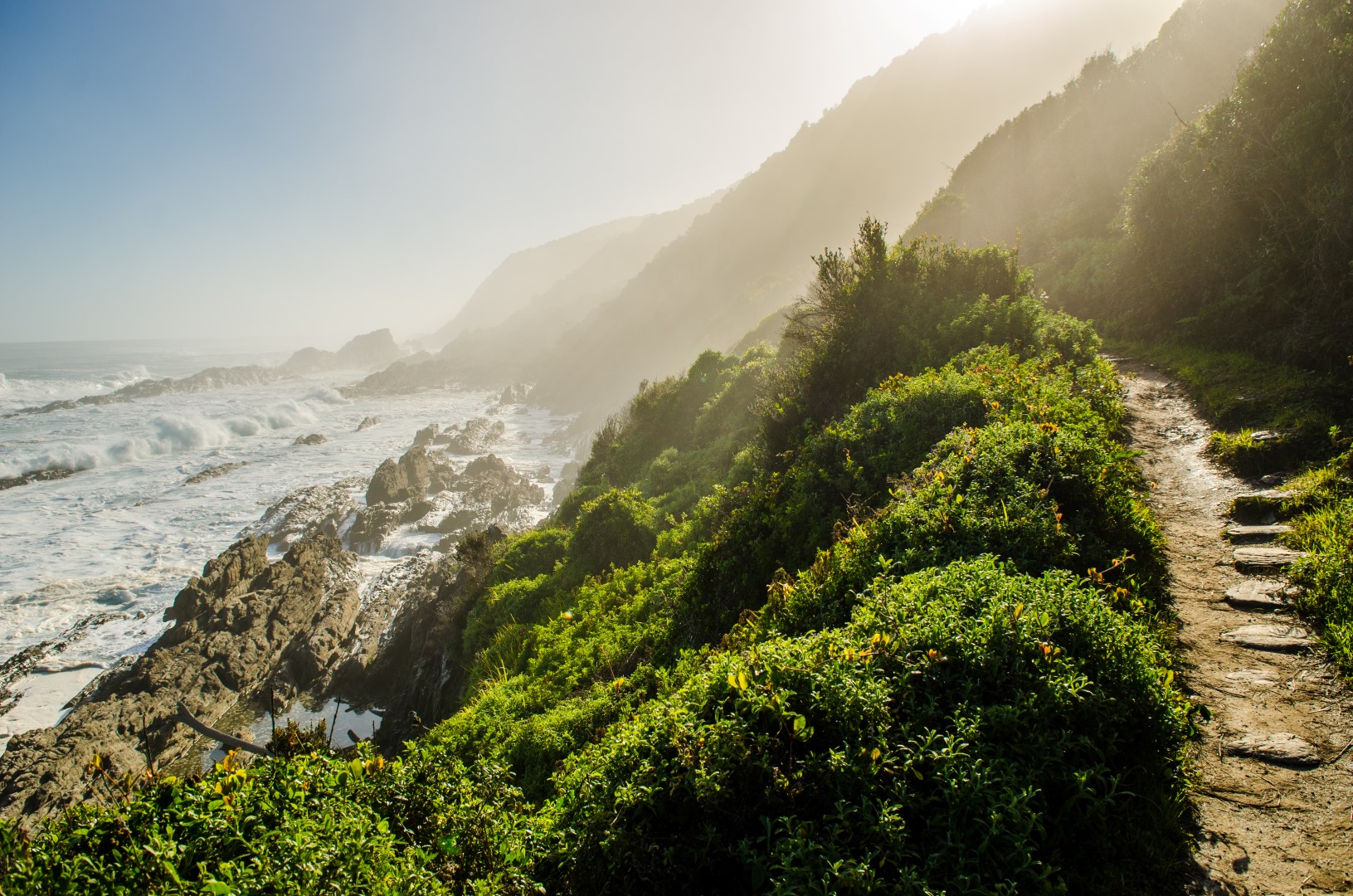 tsitsikamma-garden-route A rugged coastal path winds past green cliffs and crashing waves, capturing the wild beauty of Africa in September